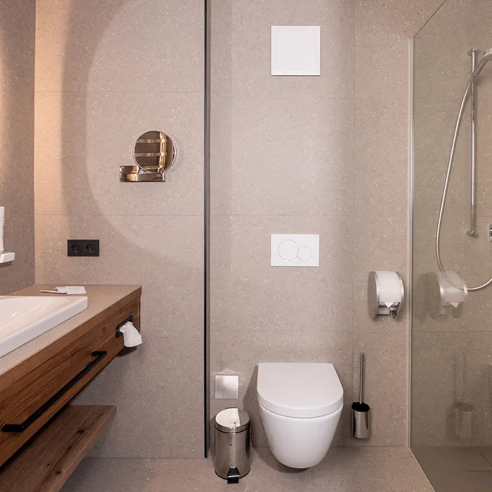 Modernes Hotelbad mit begehbarer Dusche, wandhängendem WC und Holzwaschtisch mit breitem Waschbecken